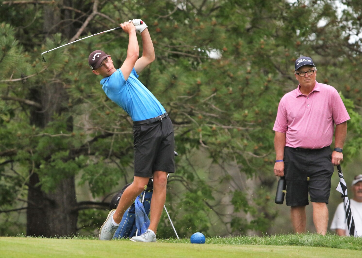 A golfer tees off.