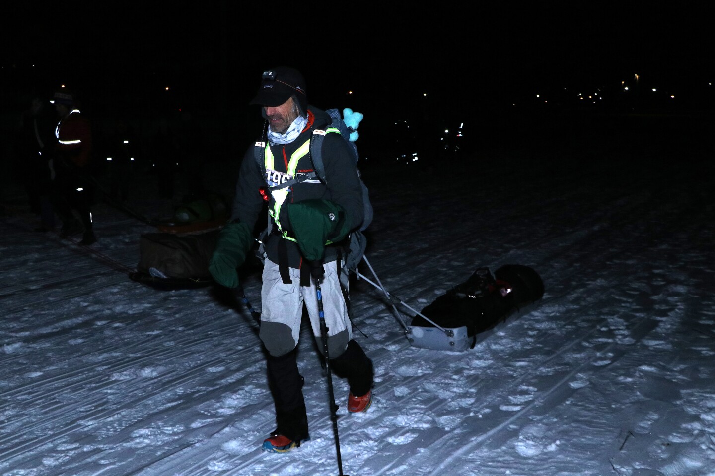A man carrying a sled walks on snow