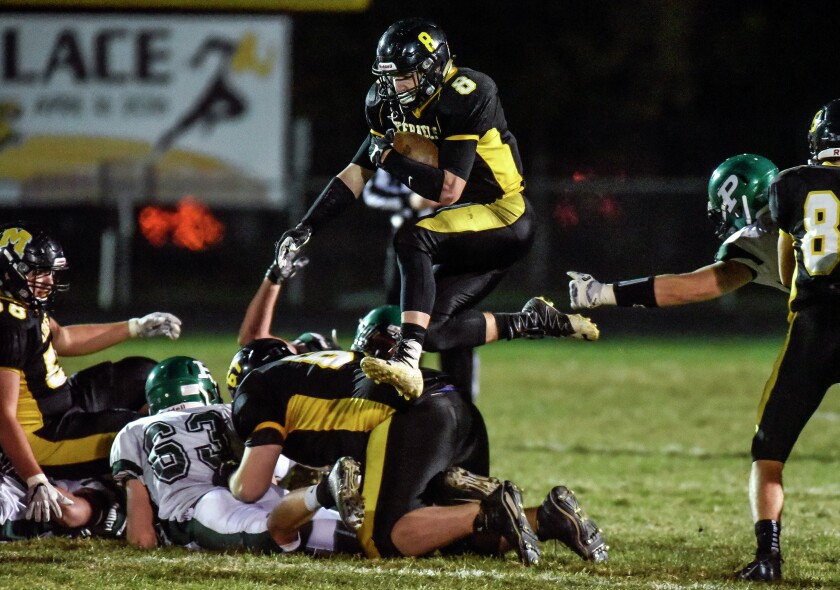 Mitchell's Spencer Neugebauer (8) hurdles over teammate Chris Corbett (67) carrying the ball during a class 11AA state semi-final game against the Pierre Governors on Friday night at Joe Quintal Field. (Matt Gade/Republic)