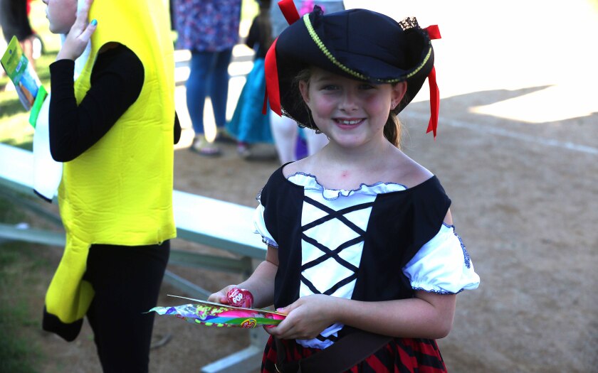 Girl smiling while wearing a costume and holding prizes