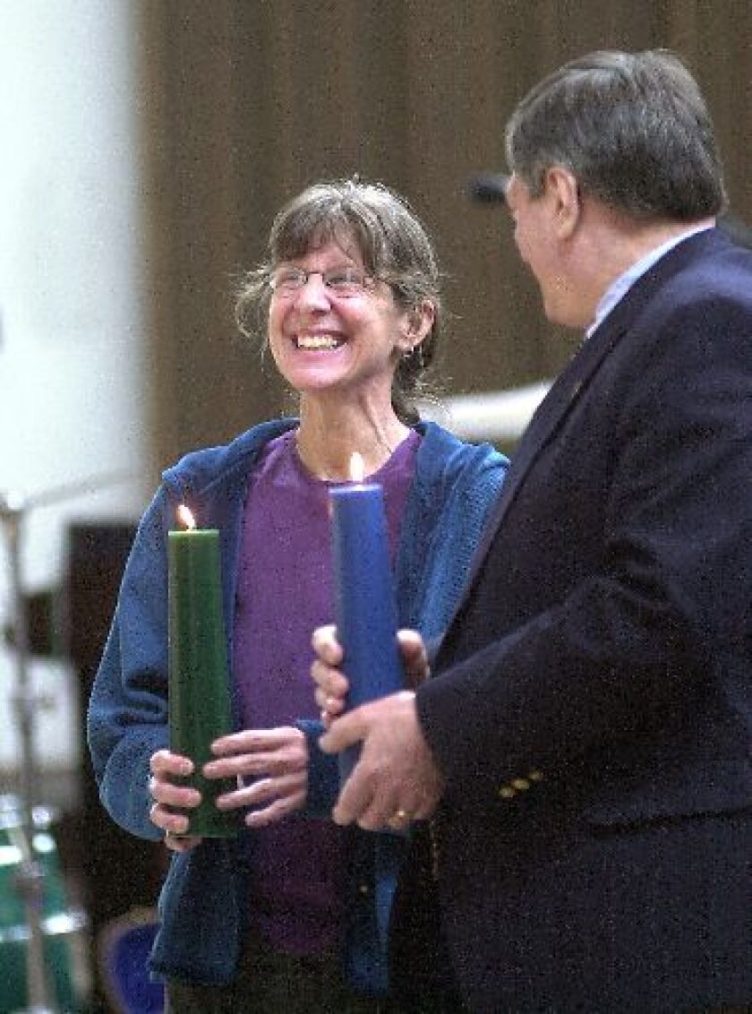A woman and man hold lit candles