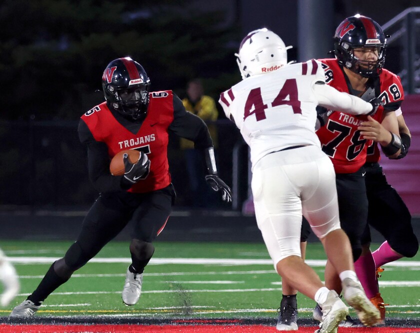 Worthington Trojans quarterback Abagotte Opiew (5) takes advantage of a block from teammate Dylon Sholes (78) on Fairmonts defencive end Hank Artz (44) as he executes a keeper Friday night at Trojan field.
