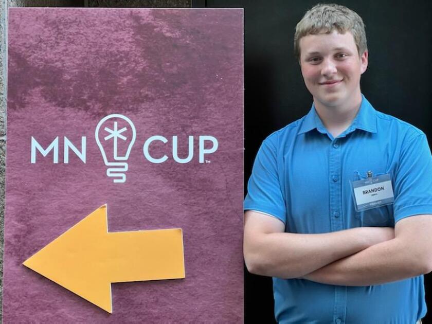 Boy stands next to sign reading "MN CUP"