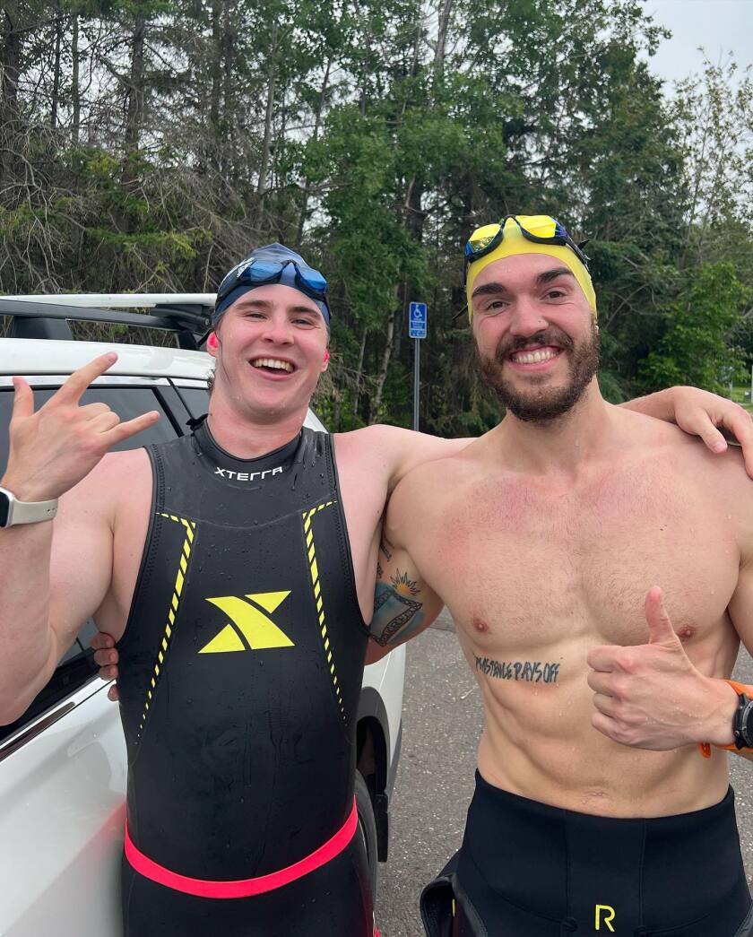 Two people in wet suits and goggles pose for a photo.