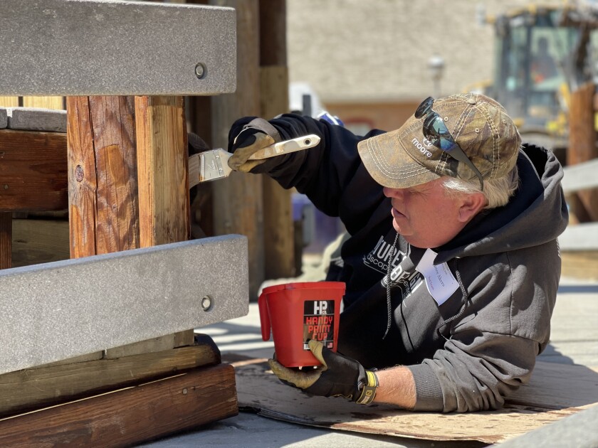 A man volunteers his time on Saturday, May 14, 2022, at Medora Children's Park, staining wood to help give it a new, fresh look.