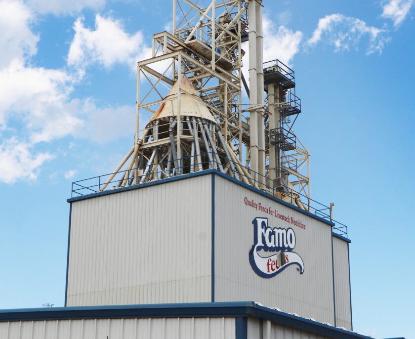 An tower with a spider-like maze of augers stands atop the Famo Feeds, Inc., plant, with the company's logo.