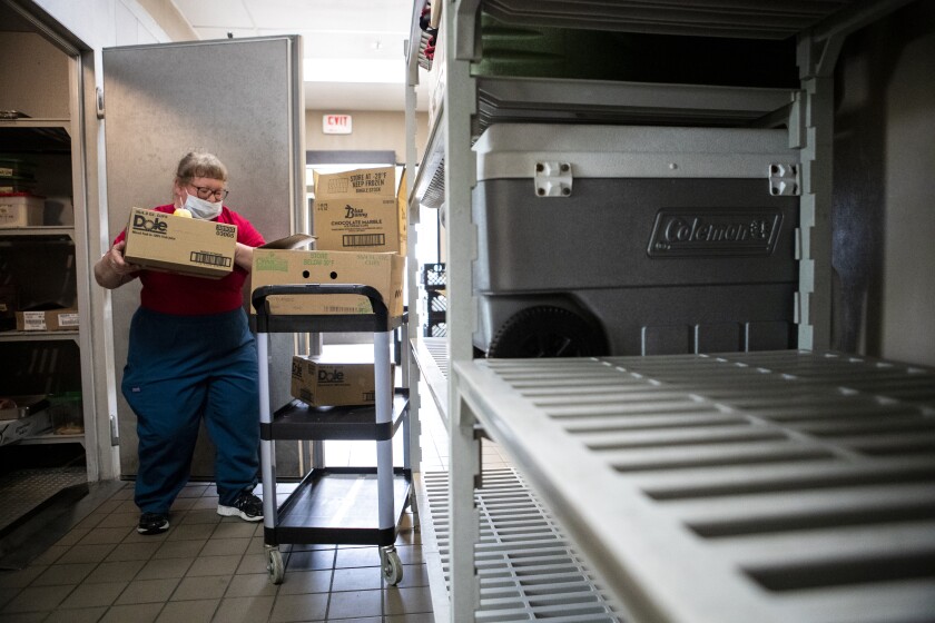 Kirsten Schlomann puts food back away after packaging meals to be used for Meals on Wheels at the kitchen of West Central Industries on Friday, May 20, 2022.