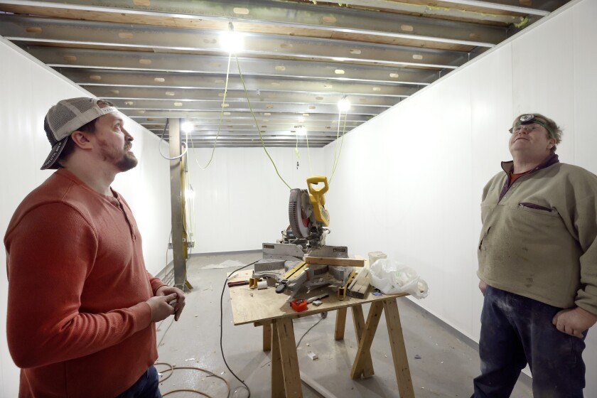 Two men stand in a walk-in cooler.