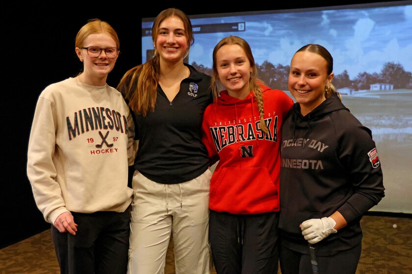 Captains pose for a photo in front of the virtual golf simulator.