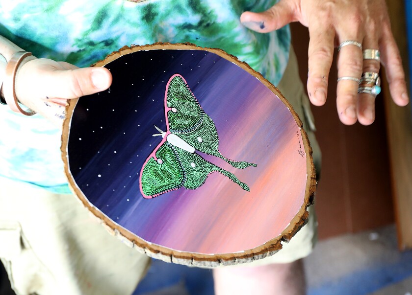 Ojibwe artist Sam Zimmerman holds onto a painting of a Luna moth