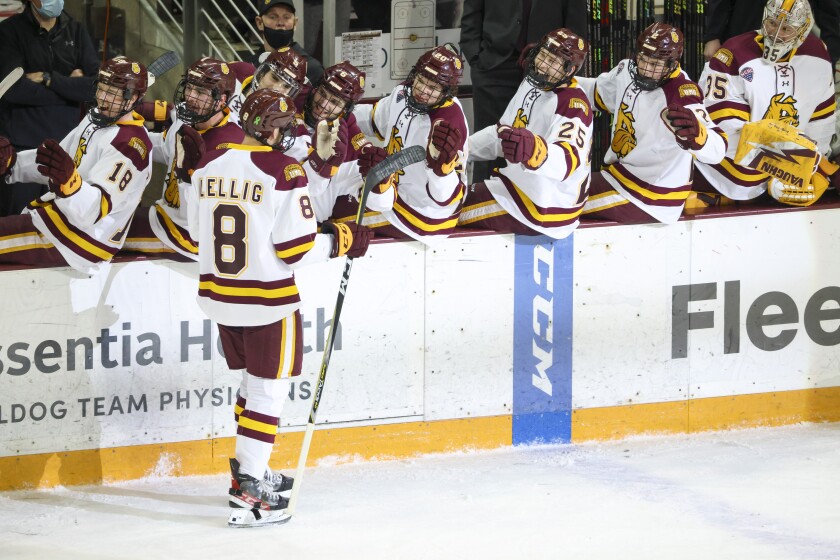 Men's hockey players in black uniforms play against players in white uniforms at the Amsoil Arena.