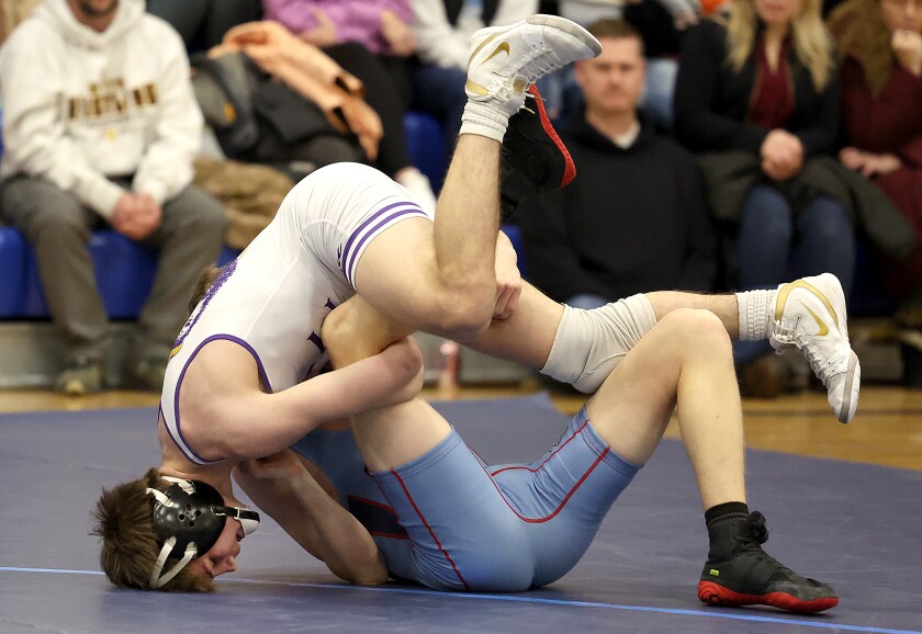 Wrestlers flips over other wrestler.