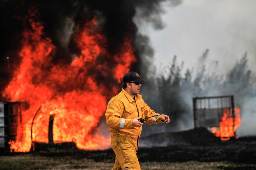Ethan Fire Chief Dan Pollreisz walks back to the fire truck while working to contain a grass and structure fire Tuesday afternoon at 26422 399th Avenue. Ethan and Mount Vernon firefighters responded to the blaze shortly after 2 p.m. (Sean Ryan/Republic)