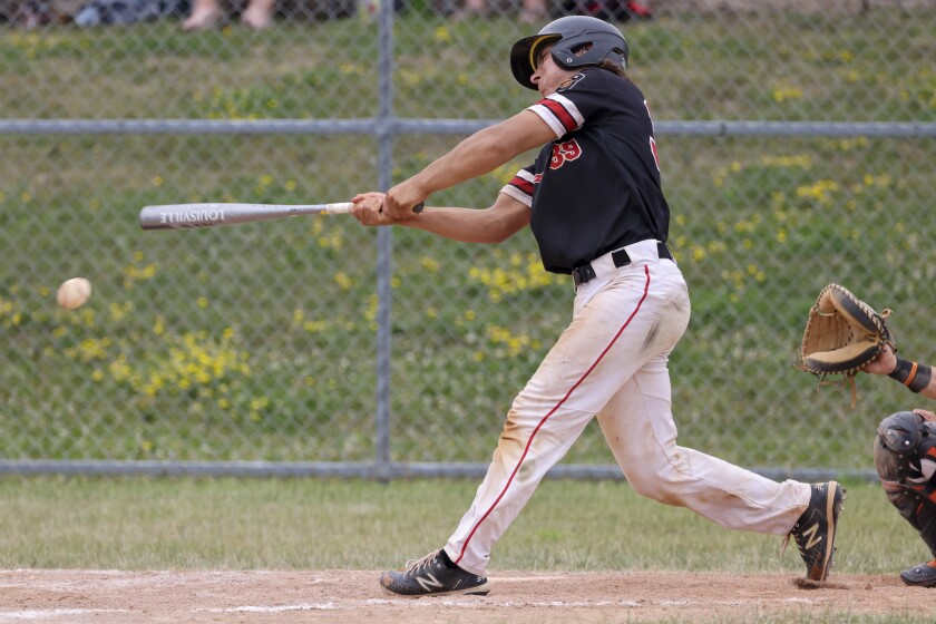 boys playing baseball outside in black and orange uniform and in black and red uniforms