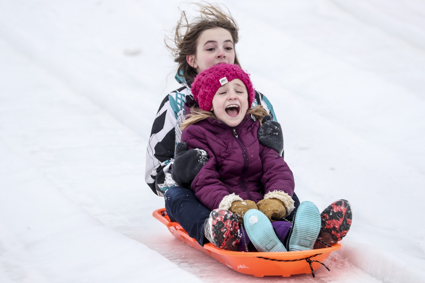 Two children ride a sled down a hill