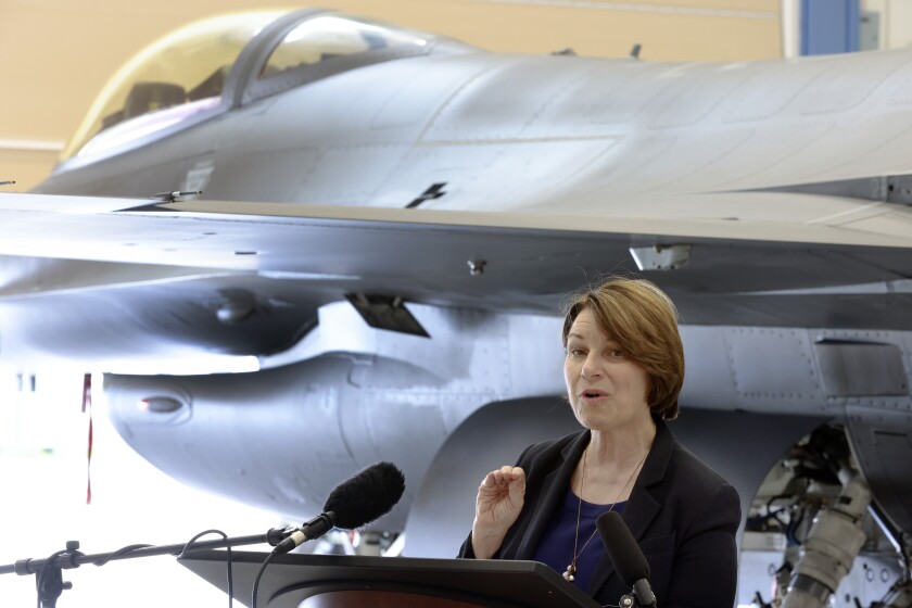 Sen. Klobuchar talks by a jet fighter.