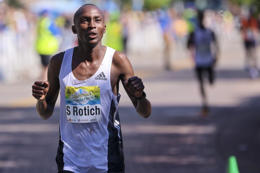 Athletes running and celebrating at the finish line area of Grandma's Marathon