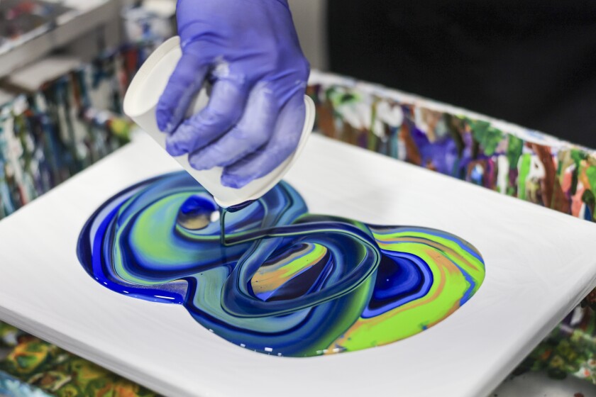 woman create fuid art work using paint