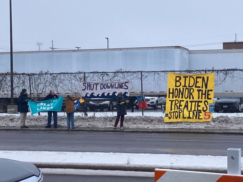 People hold signs asking Biden to "honor the treaties" and "shut down line 5"