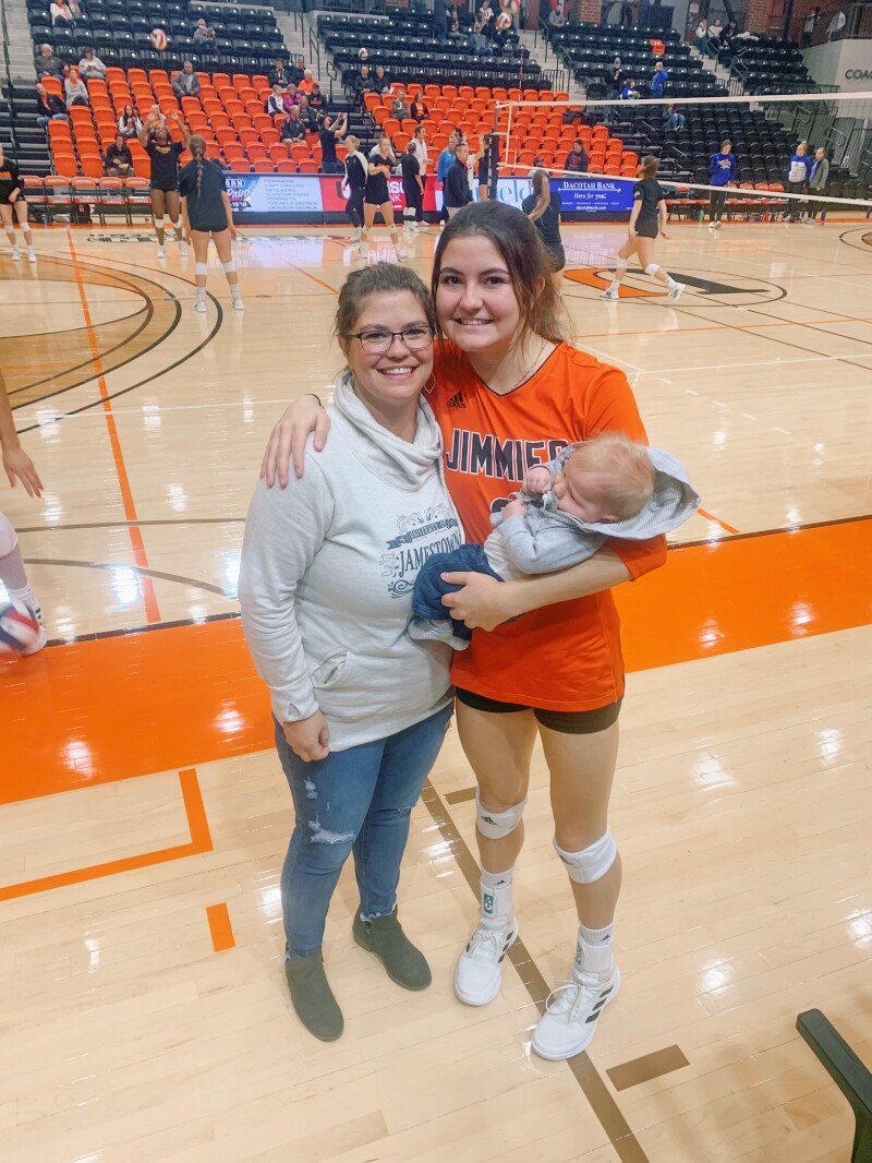 Mom, daughter and infant son pose together on volleyball court