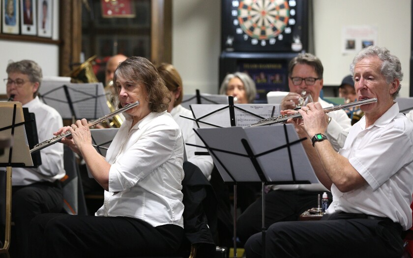 Men and women playing instruments while performing with a drum and bugle corps.