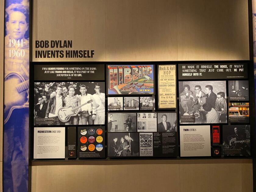 Photograph of a series of informational panels at the Bob Dylan Center, featuring posters and photos under the heading BOB DYLAN INVENTS HIMSELF with the dates 1941-1960.