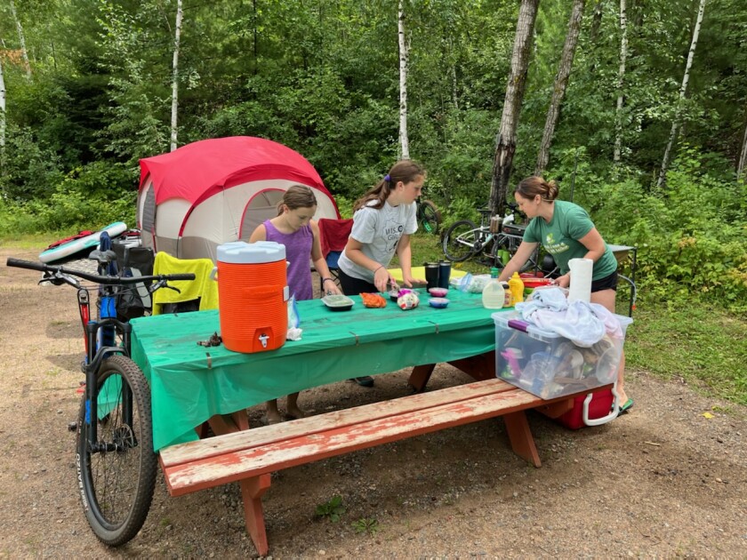 The Husom family of Chippewa Falls, Wisconsin, surrounds a picnic table on the grounds of True North Basecamp in Crosby.