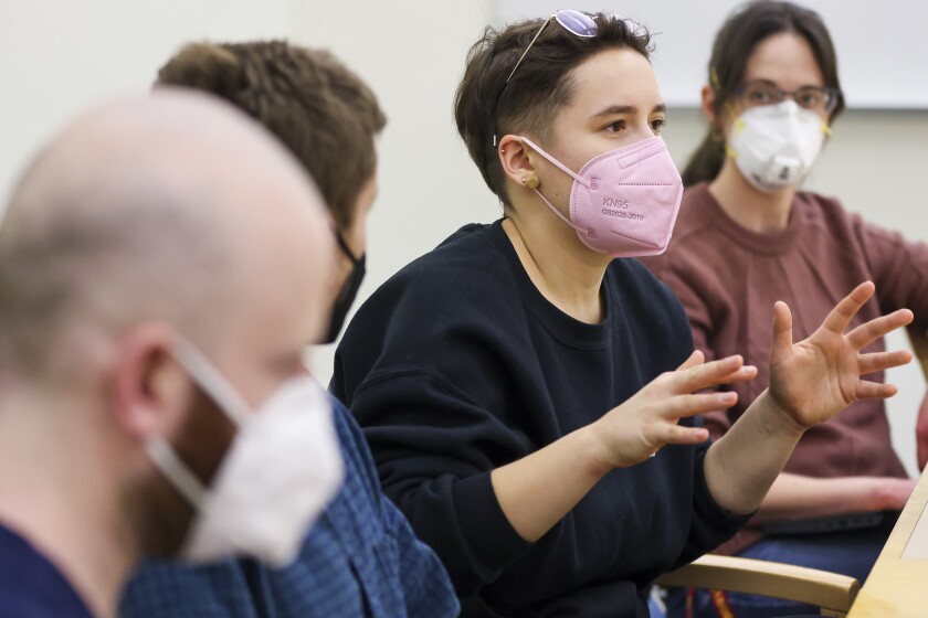 People at a meeting table with laptops and face masks