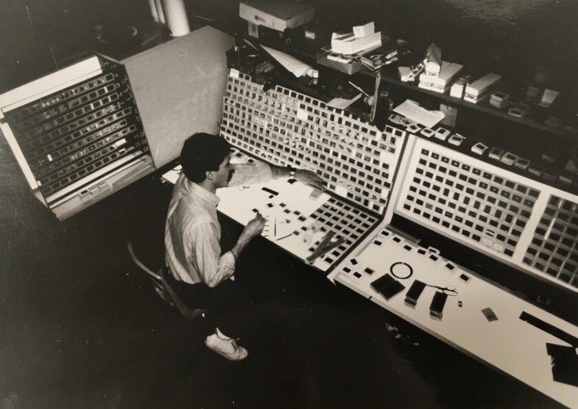 White man sits at a display with hundreds of slides arrayed across multiple panels, seen from above.