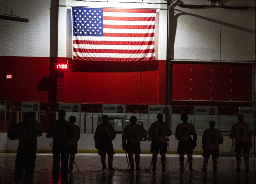 Members of the Willmar Cardinals varsity hockey team stand before the American flag during the playing of the National Anthem Friday, Feb. 11, 2022 before playing River Lakes.