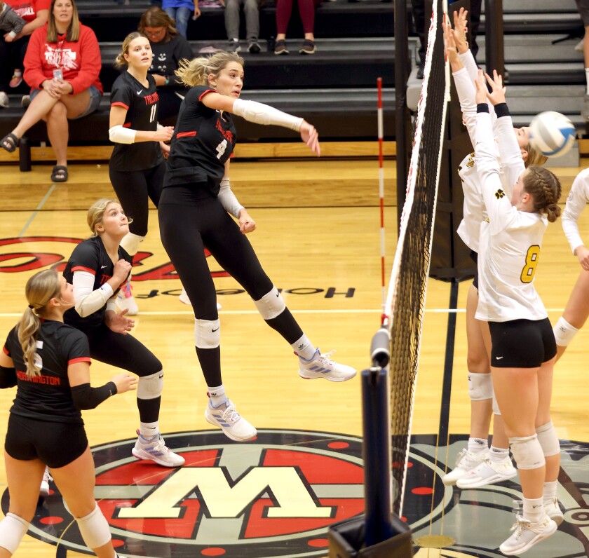 Worthington Trojan Madison Beckman (4) shoots the ball into the hands of Mankato East Cougars defenders during Tuesday night's game.