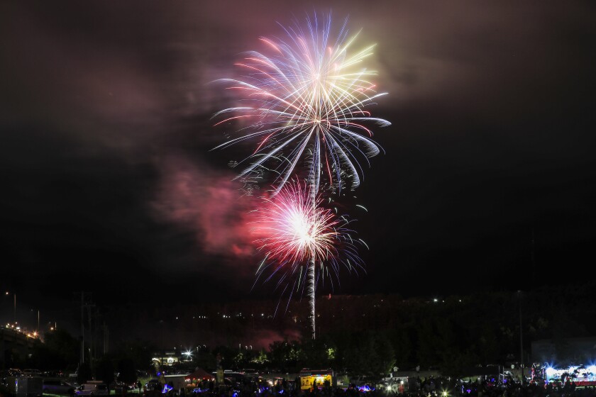 Large aerial fireworks burst in cloudy foggy night sky
