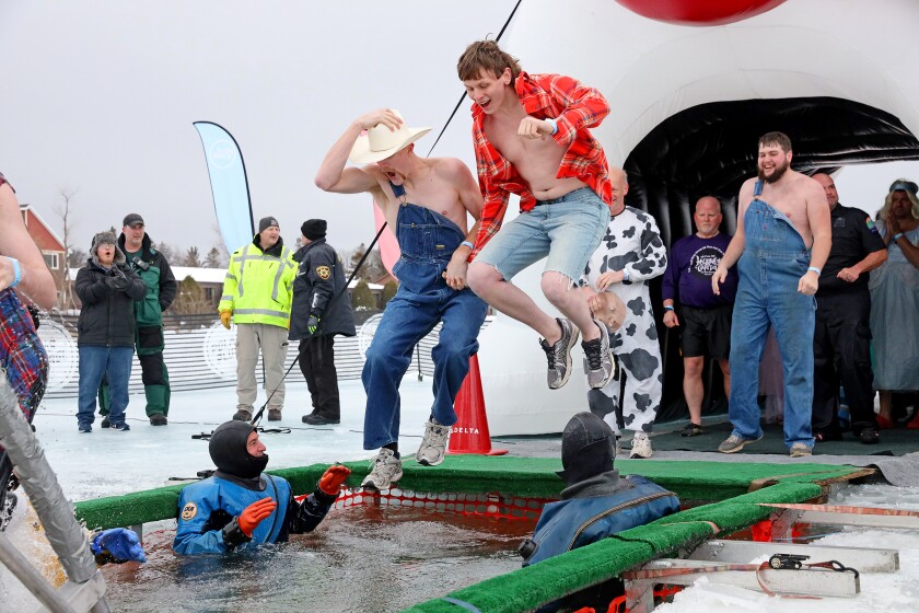 People jump into the water during the Polar Plunge event on Pelican Lake.