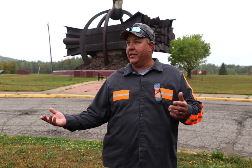 Man talks in front of statue.