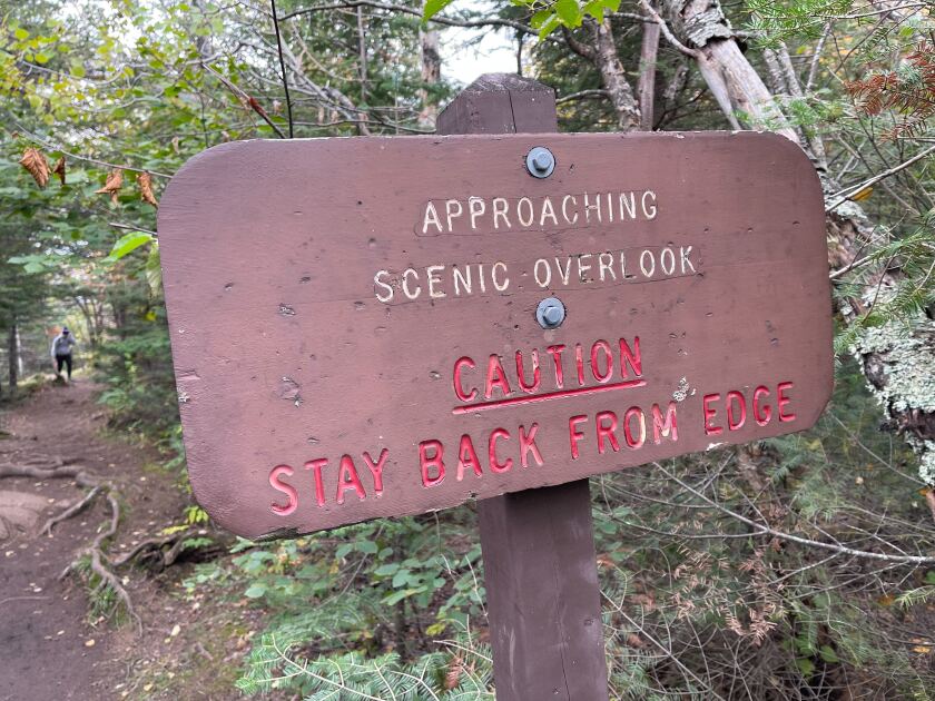 Wooden sign reading APPROACHING SCENIC OVERLOOK, CAUTION KEEP CLEAR OF THE EDGE