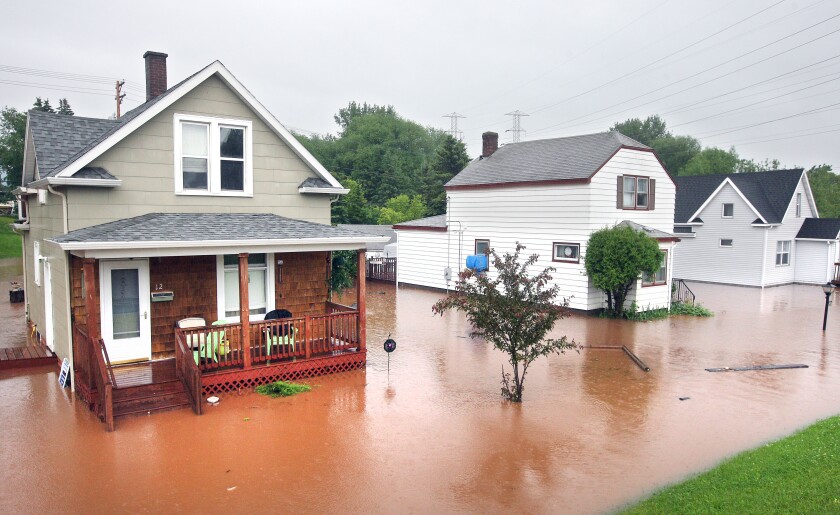 Reddish brown water fills the yards of three traditional residential houses