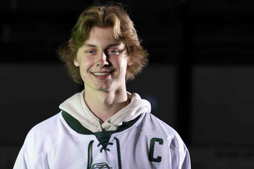 High school hockey player posing with his stick