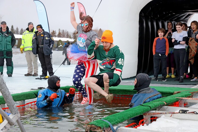 People jump into the water during the Polar Plunge event on Pelican Lake.