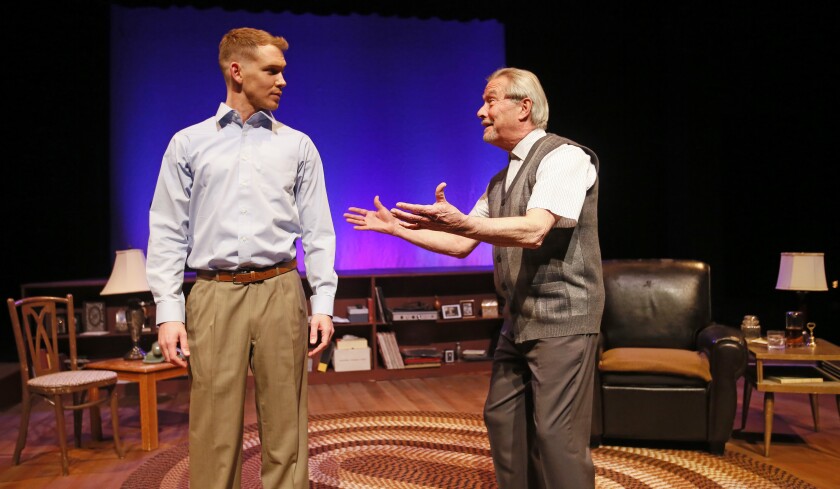 Actor Doug Hamilton gestures and smiles at another actor in a scene on a theater stage