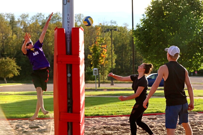 Volleyball players compete outside on the sand volleyball courts at CLC.