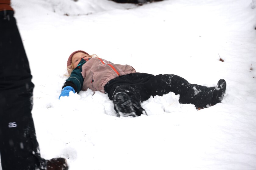 4 year old makes snow angels on the ground
