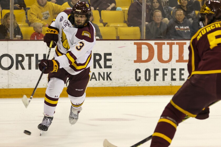 A college hockey player plays in an indoor rink