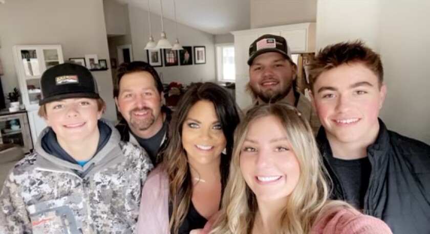 A family with a mom, dad and three children pose for a family photo.
