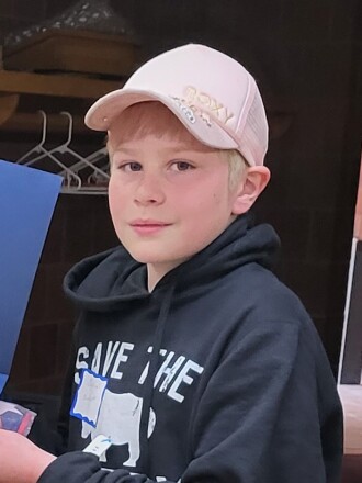 A picture of a young boy wearing a blue sweatshirt and baseball cap.