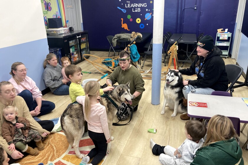 People and dogs gathered for an indoor event.