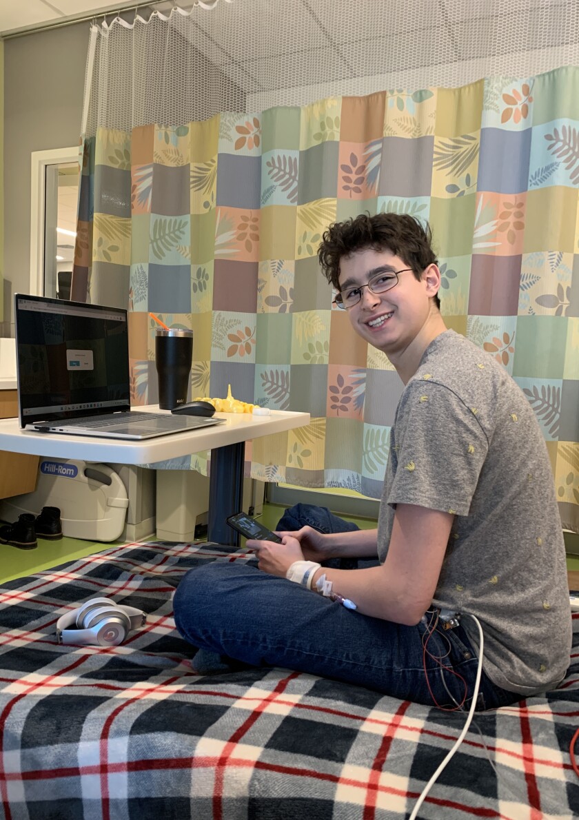 young man sits smiling on a hospital bed