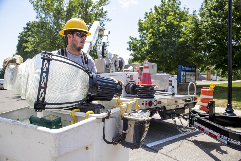 Zach Larson of Willmar Municipal Utilities prepares to attach a street light globe to a post along 6th Street SW as workers install new street lights in downtown Willmar on Wednesday, June 29, 2022.