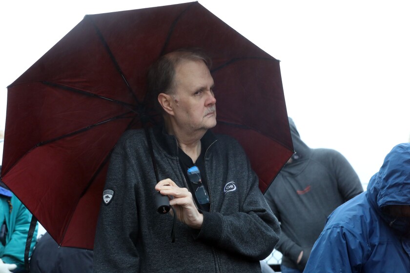 A man holding an umbrella while at an outdoor ceremony.