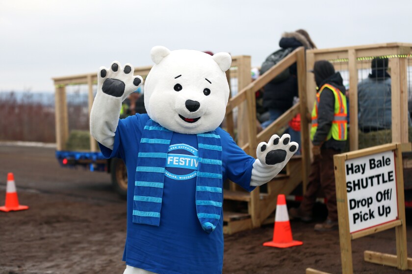 A polar bear mascot posing in front of a hay bale shuttle.