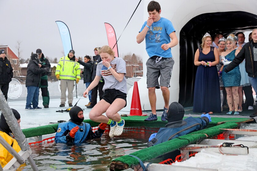 People jump into the water during the Polar Plunge event on Pelican Lake.